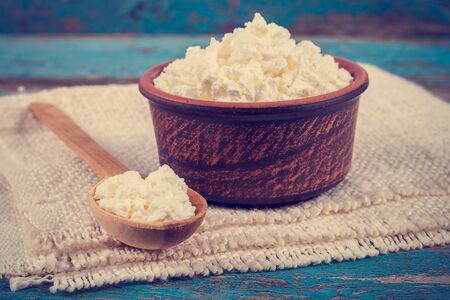 Fresh cottage cheese in a ceramic dish and spoon on painted blue wooden boards.の写真素材