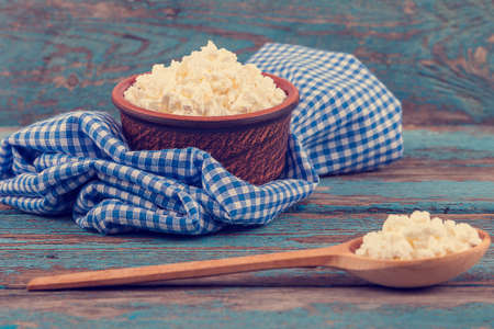 Fresh cottage cheese in a ceramic dish and spoon on painted blue wooden boards.の写真素材