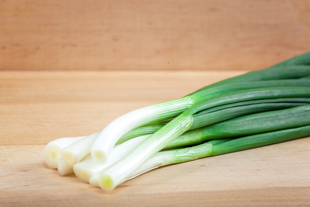 Fresh green onions on a wooden board.の写真素材