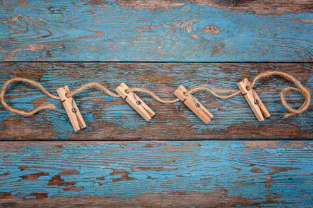 Clothespins with a rope on blue wooden boards.