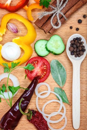 Slices of vegetables and spices on wooden table.の写真素材