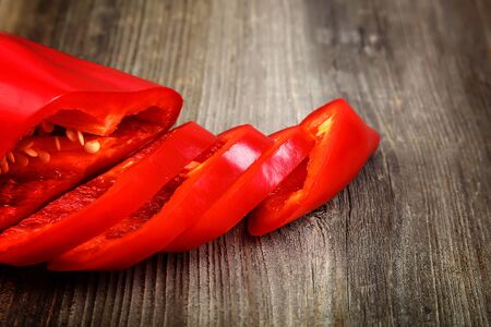 Slices of red bell pepper on a wooden background.の写真素材