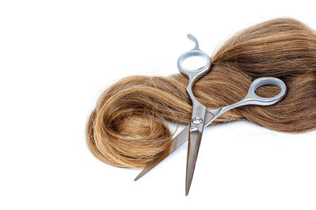 Professional hairdressing scissors and a lock of blond hair isolated on white background.の写真素材