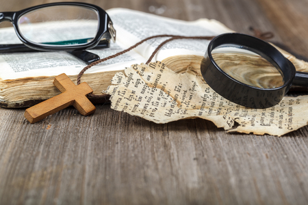 Ancient holy book of a wooden cross on a cord on a wooden background.の写真素材