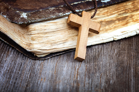 Ancient holy book of a wooden cross on a cord on a wooden background.の写真素材