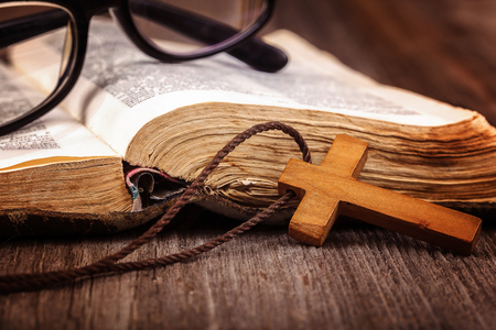 Ancient holy book of a wooden cross on a cord on a wooden background.の写真素材