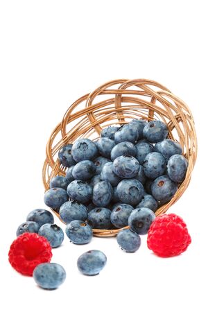 Fresh blueberries and raspberries in wicker baskets isolated on a white background.の写真素材