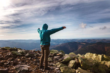 Young man traveler stands on top of a mountain.の写真素材