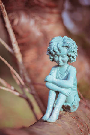 A little fairy statue sitting on a tree branch.の写真素材
