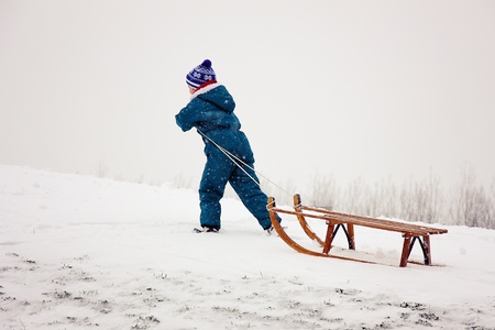 boy pulling his sleigh up the hillの写真素材