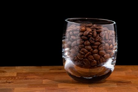 coffea beans in glass on wooden table, black backgroundの写真素材