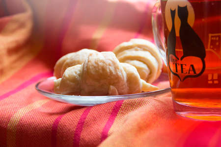 Baked goods are located on the bright fabrics with a cup of teaの写真素材