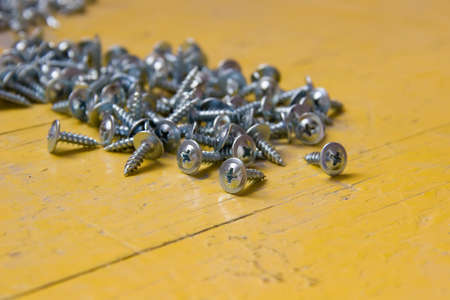 On the yellow table are scattered bunch of screws.
