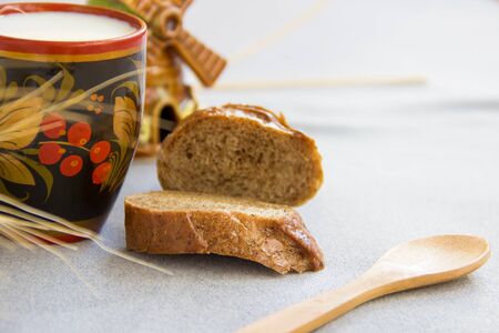 Bread and cup of milk on a gray fabric closeup in the morning light.