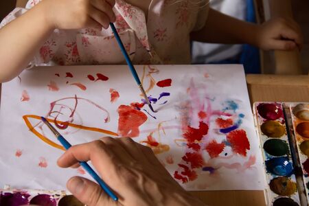 A child with an adult engaged in drawing paints. Hands only.の写真素材