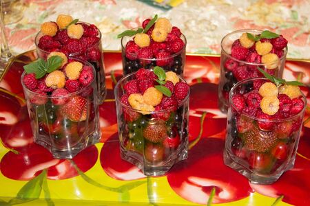 Raspberries, cherries, currants, strawberries and mint in a glass on a tray.の写真素材