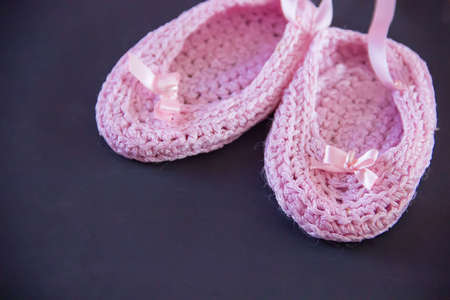 Pink booties handmade from viscose on a black background.