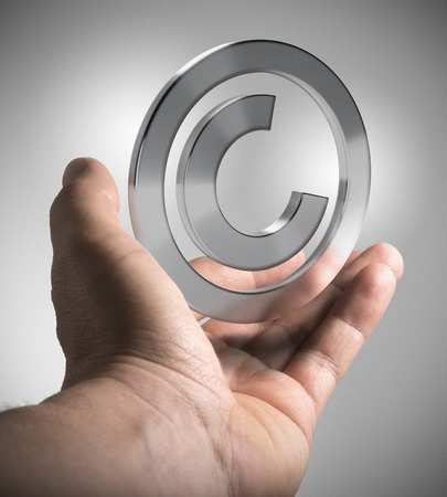 Man hand holding copyright symbol over grey background, concept image for illustration  of intellectual property.の写真素材