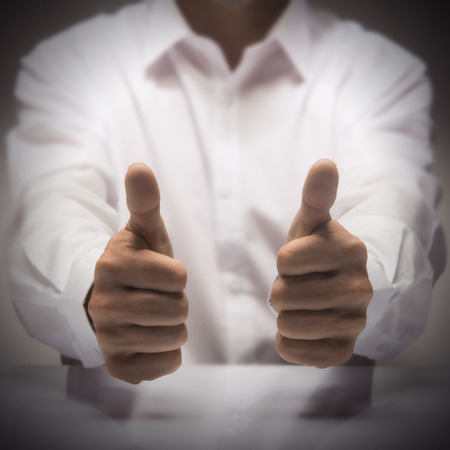 Man with two thumbs up at the background of a glossy table, concept image for illustration of excellence or best service.の写真素材