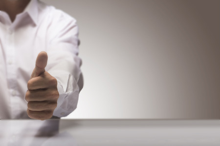 Man with one thumb up at the background of a glossy table and copy space on the right, concept image for illustration of excellent quality service.