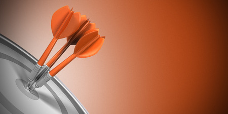 Three darts hitting the center of a target over orange background. Business success concept image.の写真素材