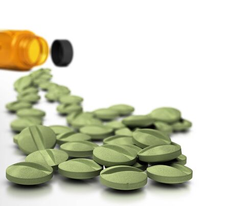 Many tablets of dietary supplements with bottle at the background over white, symbol of vitamin cure.の写真素材