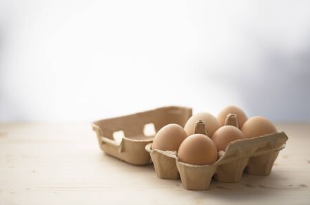 6 hen eggs in a carton box. Wooden table and free space for text, blur effect.の写真素材
