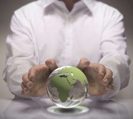 Image of a man in white shirt protect a glass earth with its hands. Earth concept for environmental protection or global business.の写真素材