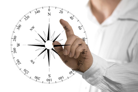 Finger about to touch a compass rose over white background. Concept of orientation.の写真素材