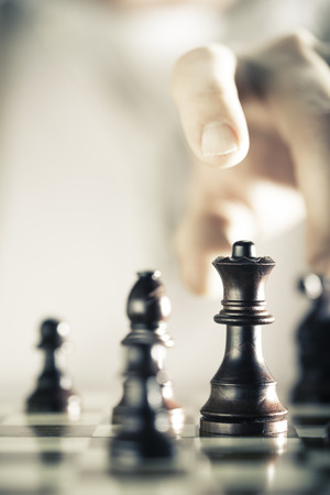 Vertical Image of a chess game with focus on the queen and a blurry hand at the backgroundの写真素材