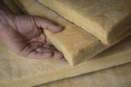 Hand holding a fiberglass batt. Image of home insulation.の写真素材