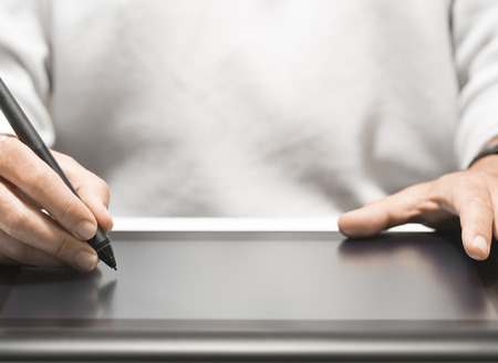 Close up of the hand of a graphic designer holding an electronic stylus. Background with free space for text, horizontal imageの写真素材