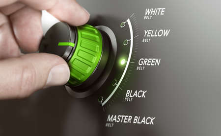 Hand turning a knob over grey background and selecting the green belt level. Lean management training concept. Composite image between a hand photography and a 3D background.の写真素材