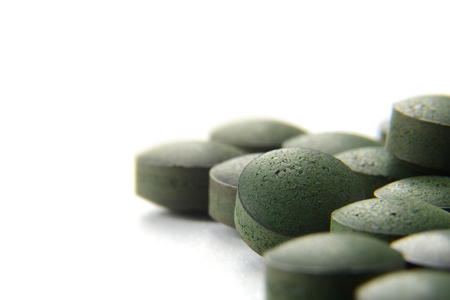 Close up of many organic spirulina tablets with low depth of field over white background. の写真素材
