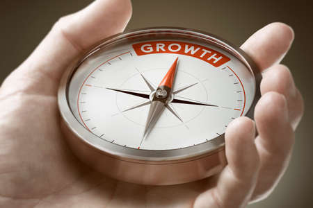 Man hand holding compass with needle pointing the word growth. Investment of financial concept. Composite image between a hand photography and a 3D background.の写真素材