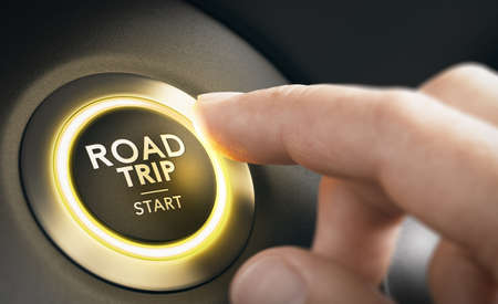 Finger pressing a car button with the text road trip start. Roadtrip concept. Composite image between a hand photography and a 3D background.の写真素材
