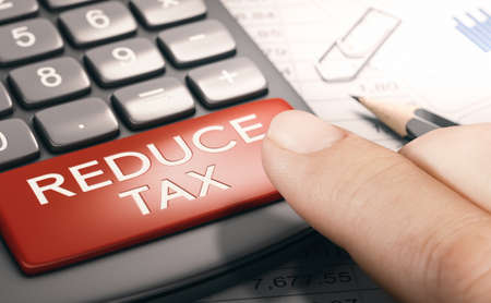 Finger pressing a red button with the text reduce tax. Lowering taxable income. Finance concept. Composite image between a hand photography and a 3D background.の写真素材