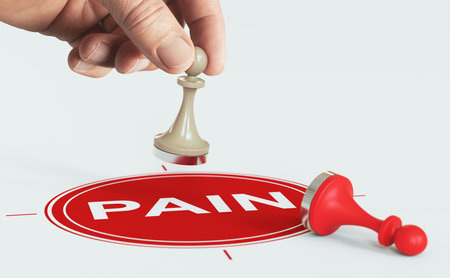Hand holding a pawn above a red target Pain relief or management concept. Composite image between a hand photography and a 3D background.の写真素材