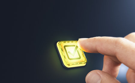 Finger pressing a yellow button with a checkmark, symbolizing validation, approval, or confirmation....