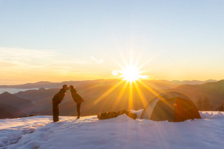 A couple kisses at sunset, camping in the snowの写真素材