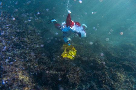 Santa Claus picks up a present underwater