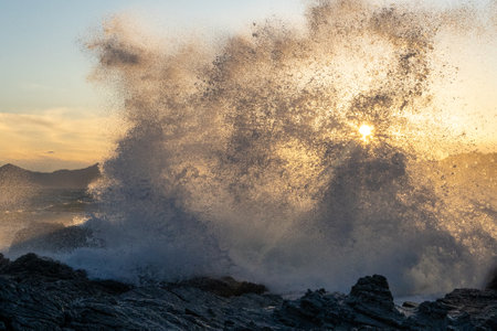 Waves crashing on cliffs at sunsetの写真素材