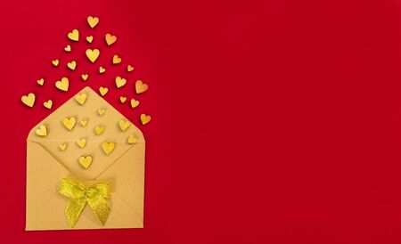 Small wooden hearts fly out of the envelope against a red background. Valentine's Day. Love concept. Gift, message for lover. Copy space.の写真素材