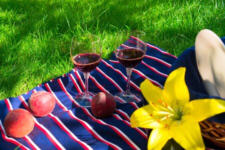 A bottle of wine, glasses, peaches, on a background of green grass. The concept of a romantic picnic in natureの写真素材