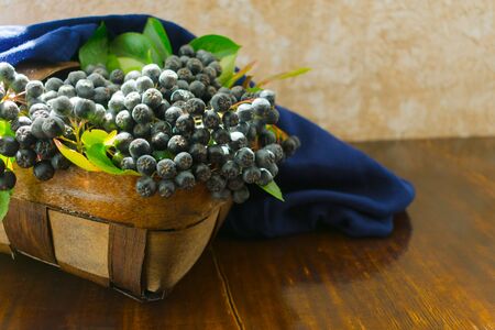 Aronia (Aronia melanocarpa) in a wicker basket on the table. Useful berry.の写真素材