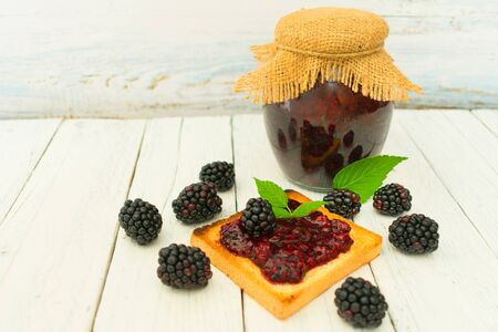Homemade jam in the bank with blackberries. Jam in a jar and fresh berries of fresh blackberry on a...