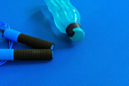 A bottle or water next to a jump rope on a yoga mat. The concept of training and rest.Sports and Healthの写真素材