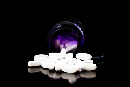 Bottle with white pills on black backgroundの写真素材