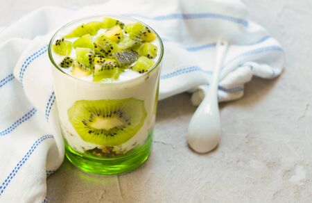 Healthy dessert with kiwi yogurt and granola on a gray background.の写真素材