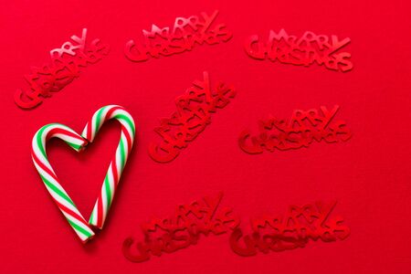 Heart made of Christmas candies and red shiny lettering with Christmas on a red background.の写真素材